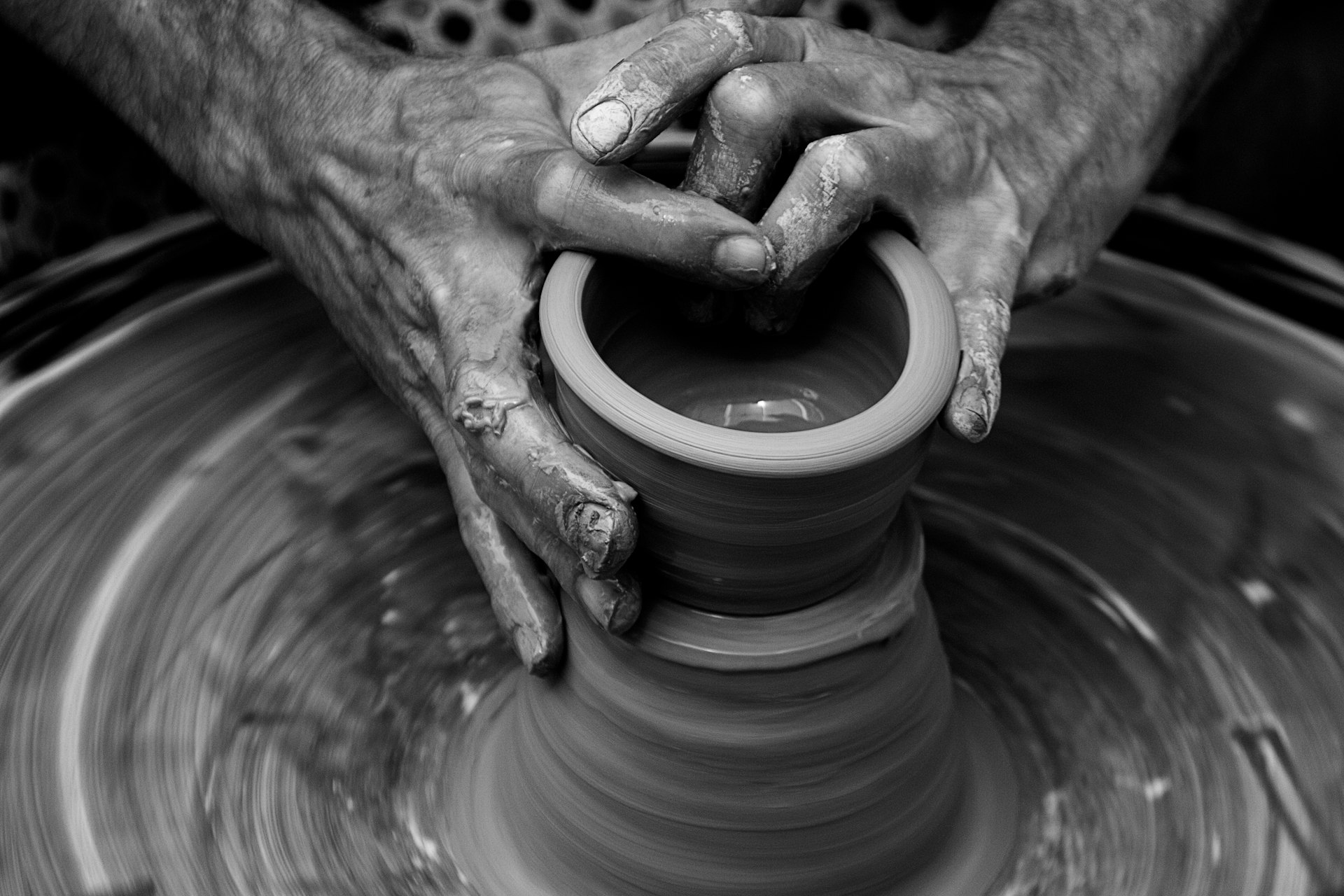 Messy hands sculpting on a pottery wheel in motion